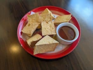 Fried tofu wedges with dipping sauce on a red-rimmed plate at Tasty Thai in Tempe.